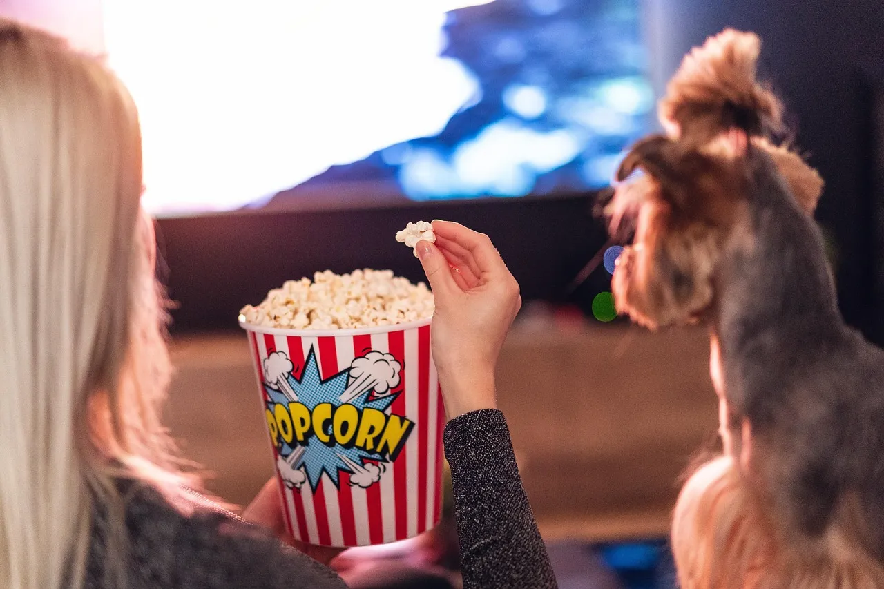 Girl and dog eat popcorn