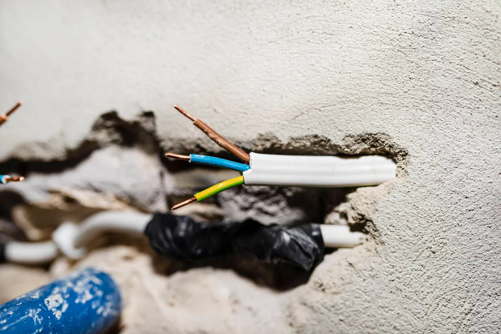 Cut single-phase cable in the wall of the house. Phase, neutral and ground wire visible